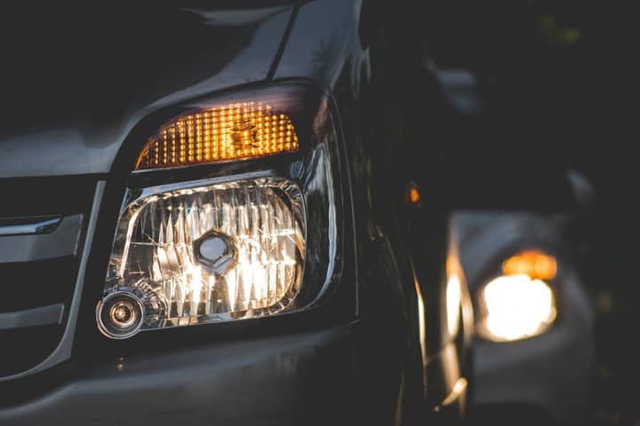 Close-up of a car's LED headlights illuminating the dark surroundings.