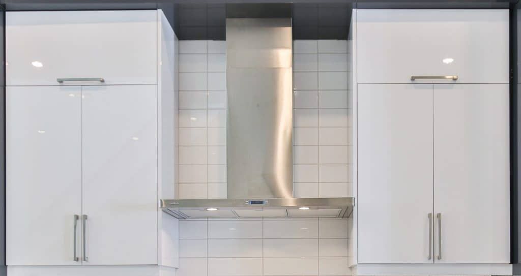 Modern kitchen with sleek white cabinets and stainless steel range hood.