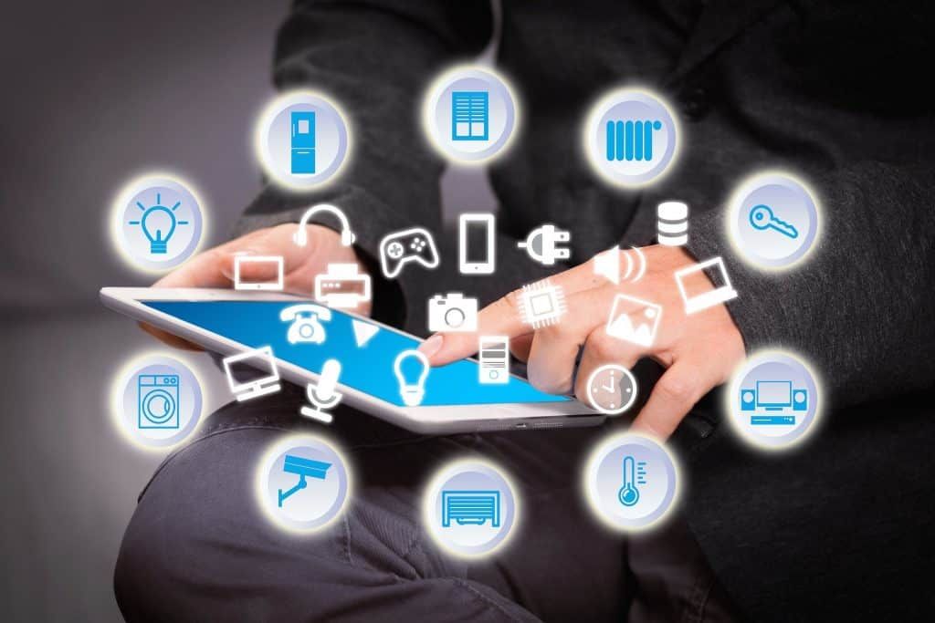 Person using a tablet displaying various smart home icons for automation.
