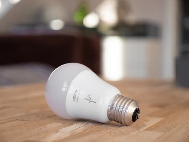 A white LED bulb lying on a wooden surface with a soft glow.