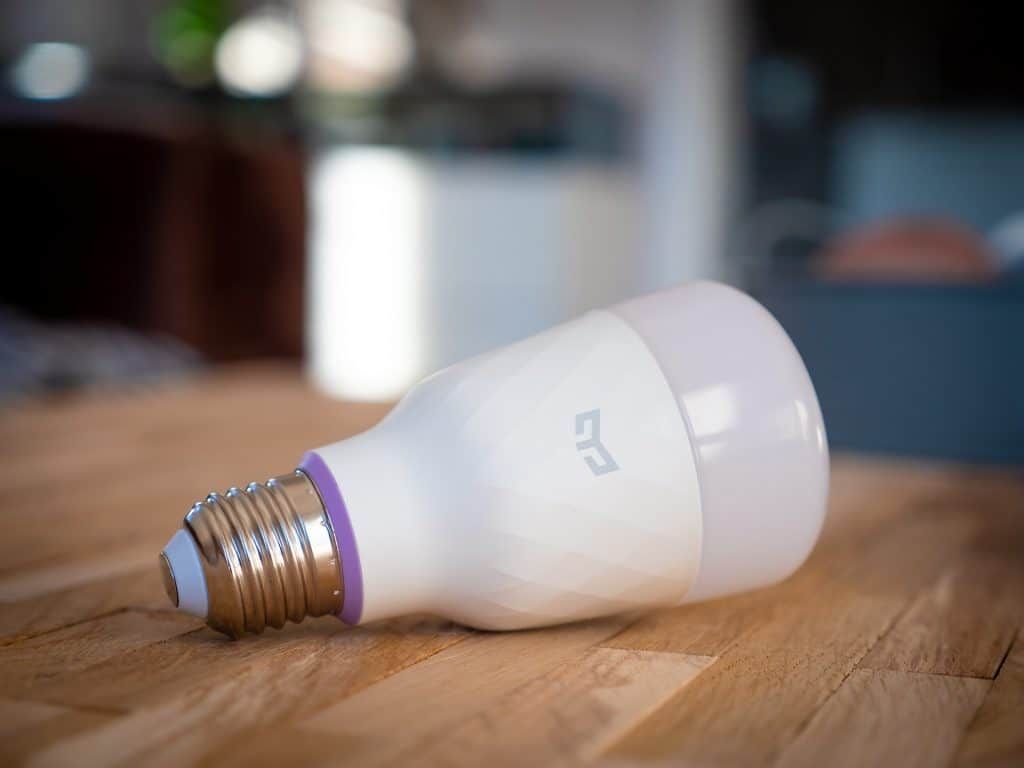 A tilted LED light bulb resting on a wooden surface with a blurred background.