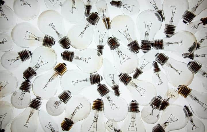A collection of light bulbs with various filament designs scattered on a white background.