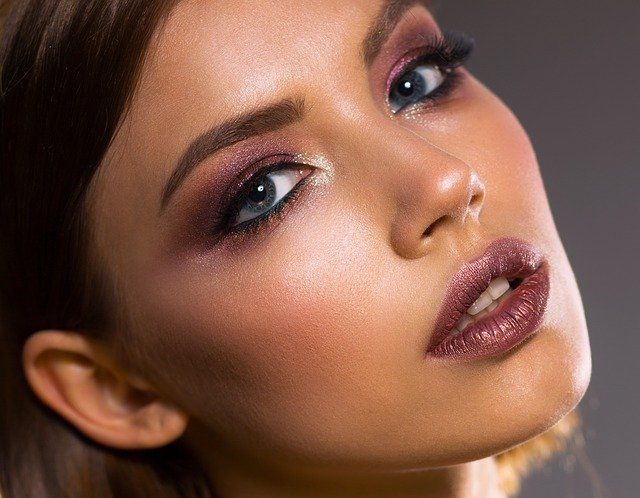 A close-up of a woman's face with dramatic makeup and soft lighting.
